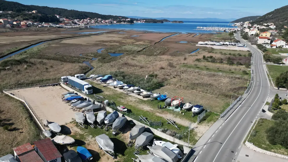 Luftaufnahme des Bootslagers Winterlager Rab in Supetarska Draga mit Booten an Land und der Bucht im Hintergrund.